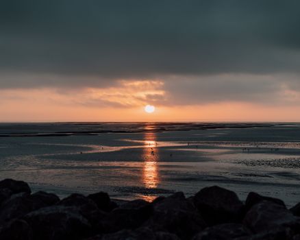 Stunning sunset view over a tranquil beach with dramatic clouds and golden reflections.