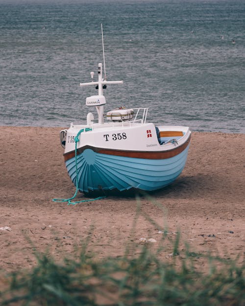 Free Fishing Boat Docked on a Sandy Shore Stock Photo