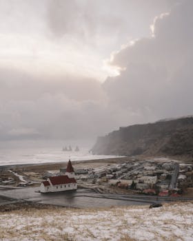 Picturesque view of Vik's iconic church with a backdrop of ocean and cliffs, Iceland.