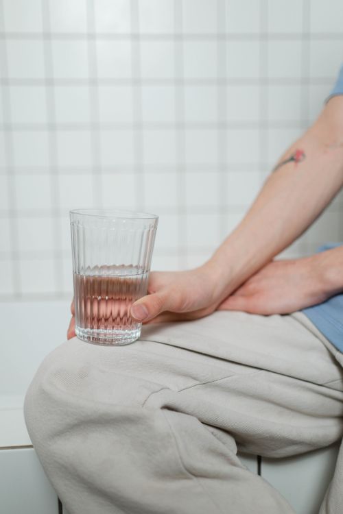 Free Close-up of a person holding a glass of water in a modern bathroom setting. Stock Photo