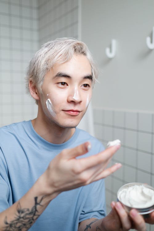 Free Man in Blue Crew Neck Shirt Putting Cream On His Face Stock Photo