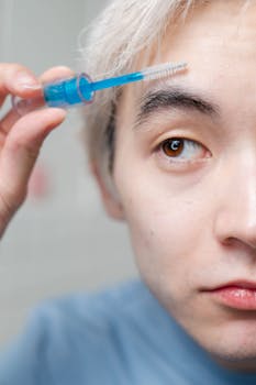 Close-up of a young man using eyebrow serum as part of his morning routine.