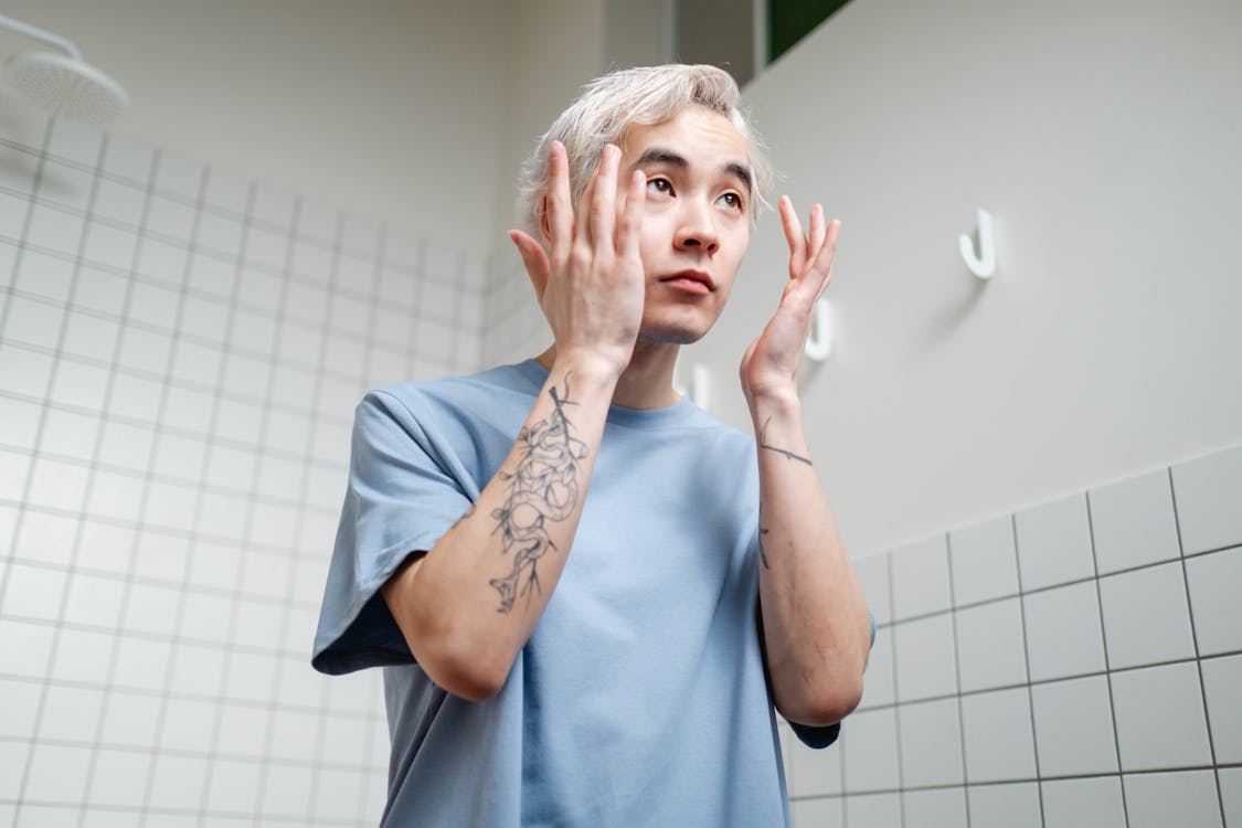 Free  Man in Blue Crew Neck T-shirt Fixing His Eyebrows Stock Photo