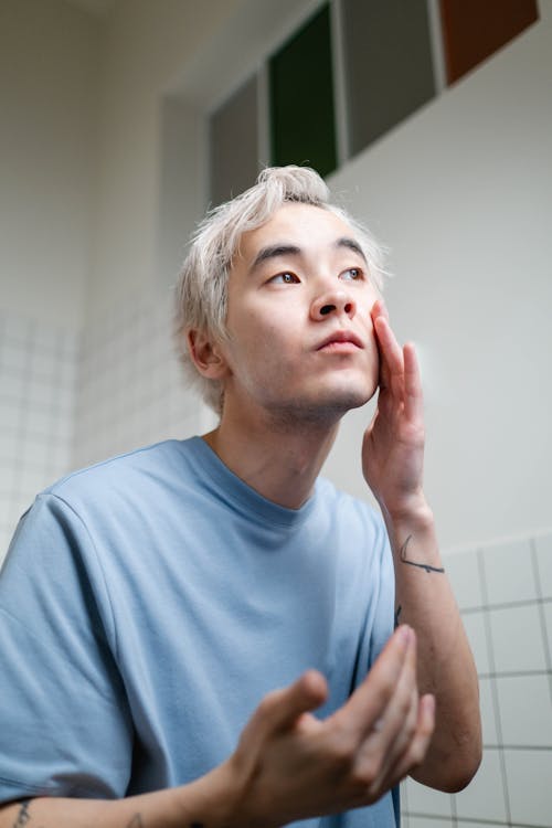 Man in Blue Crew Neck T-shirt Applying A Cosmetic Mask