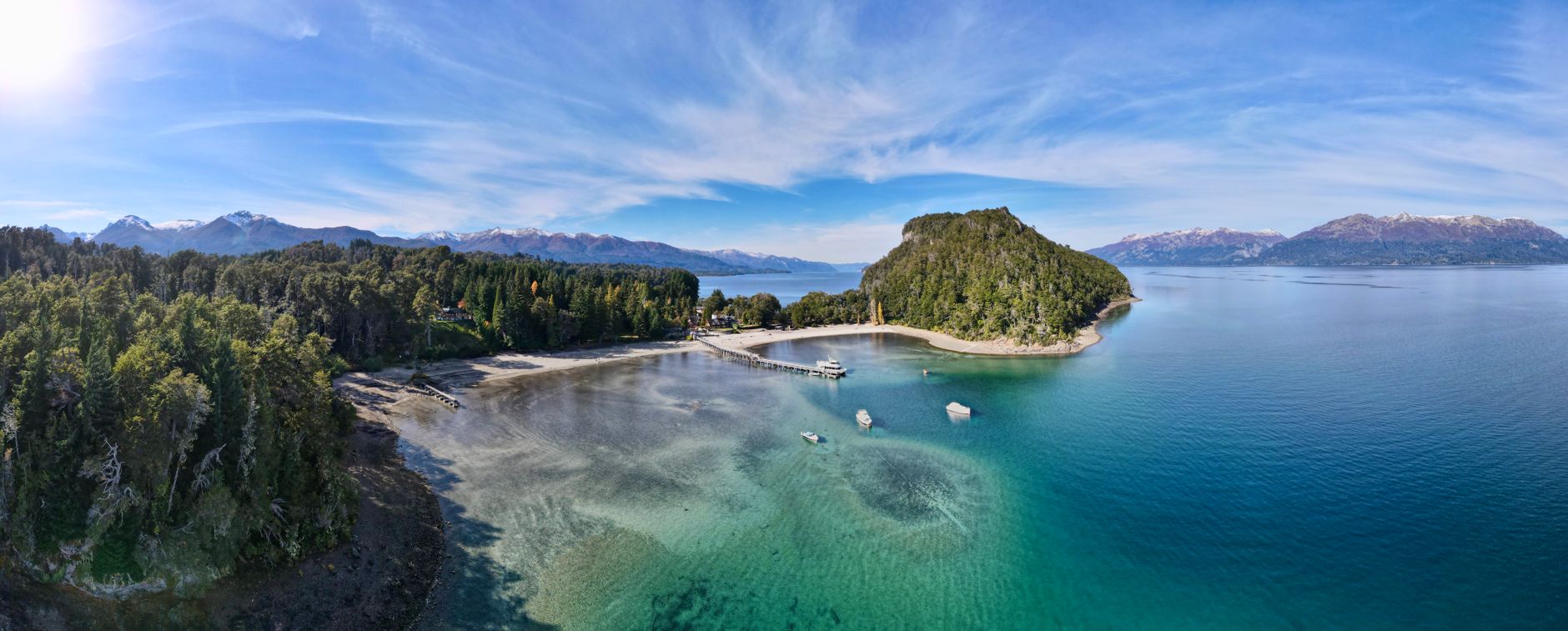A breathtaking aerial view of Isla Victoria with lush forests, turquoise waters, and distant mountains in the Andes.