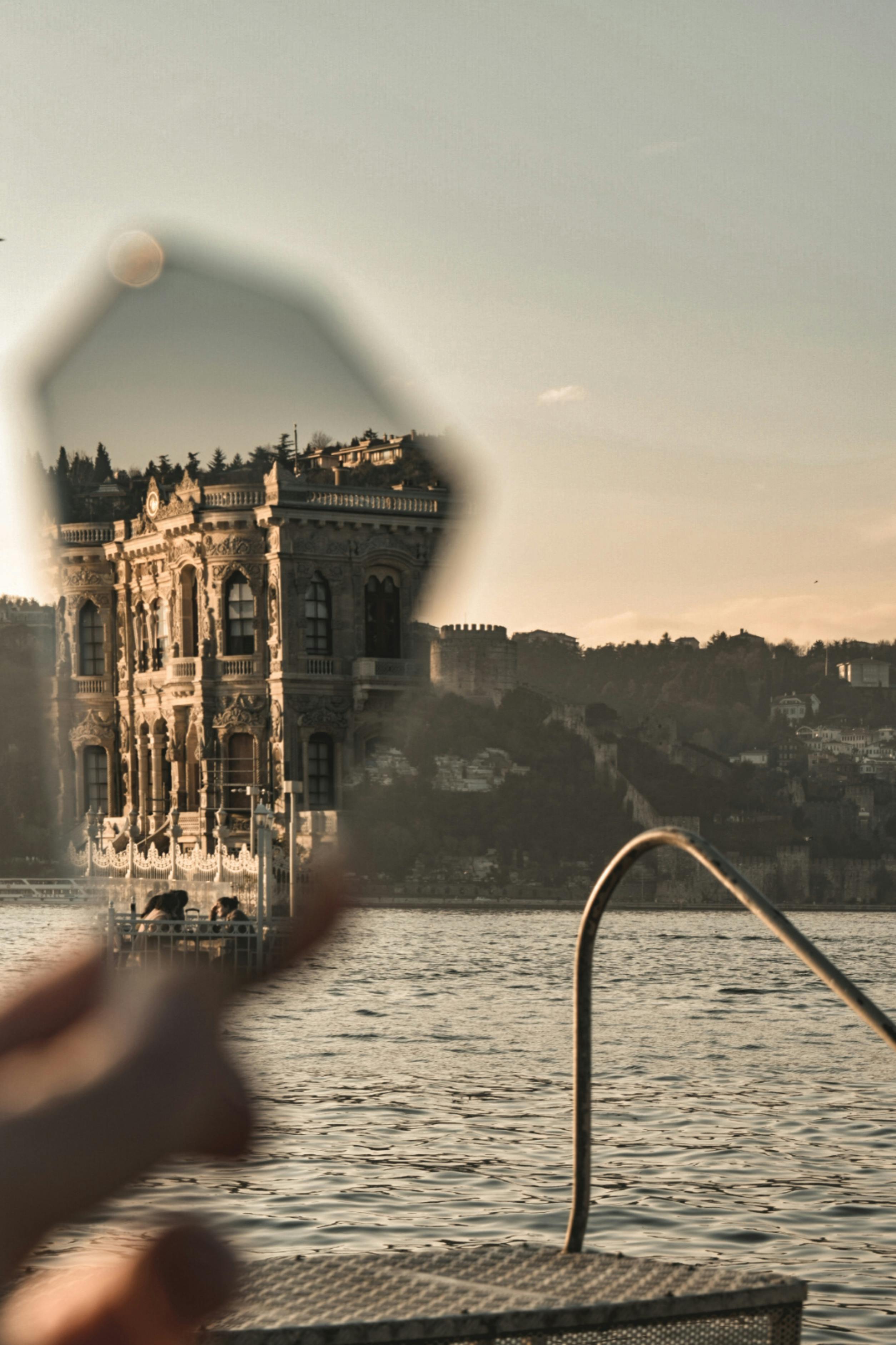 A unique reflection of an ornate building on water, captured creatively with a handheld mirror.