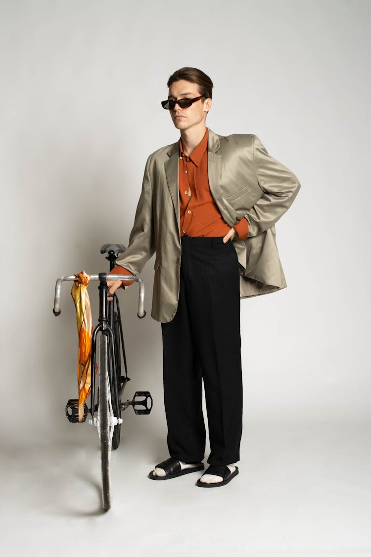 A Man In In Formal Attire With Black Slippers Standing Beside A Bicycle