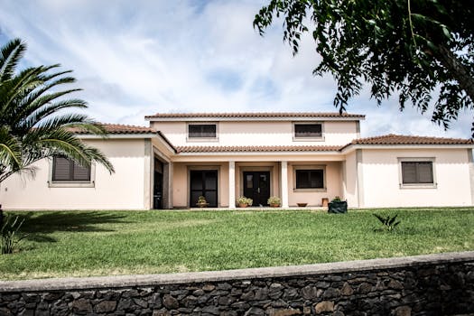 一栋时尚的现代家庭住宅，坐落在郁郁葱葱的草坪上，棕榈树在明亮的天空下摇曳