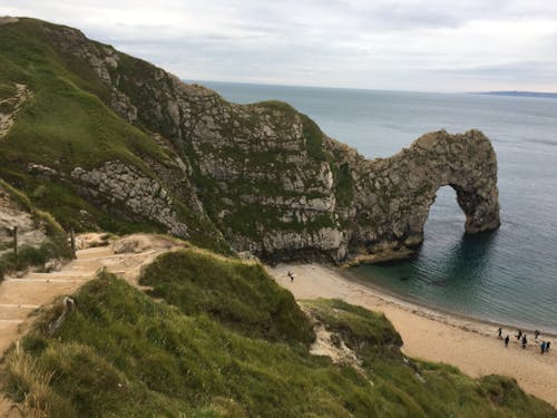 People on Beach Near Rock Formation