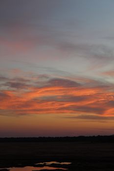 Beautiful sunset over Zimbabwe with vibrant orange and purple sky reflections creating a serene landscape.