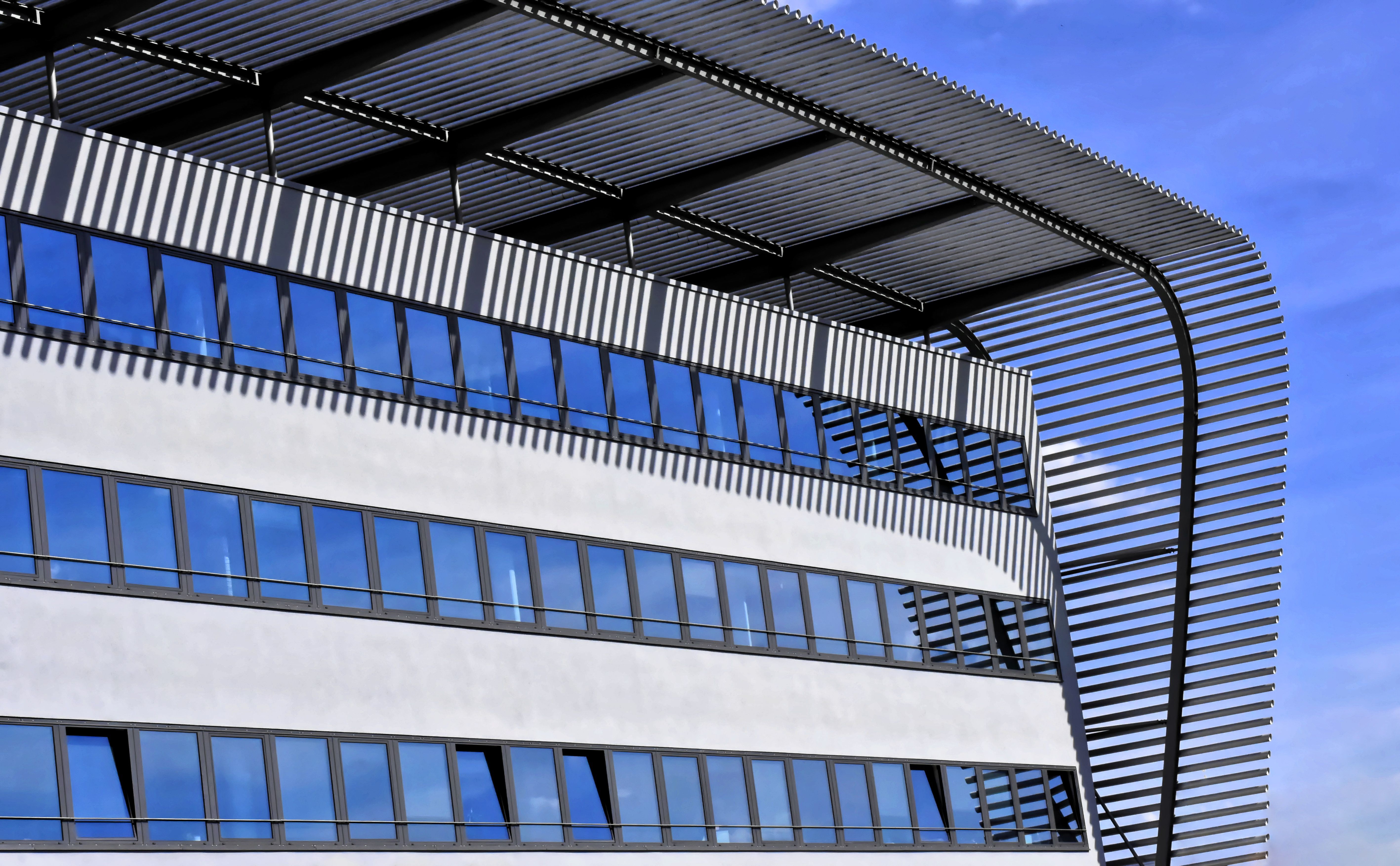 Close-up of a contemporary building with glass windows and steel roof design.