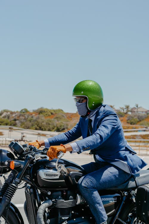 Man in Blue Suit Jacket with Green Helmet Riding on Motorcycle