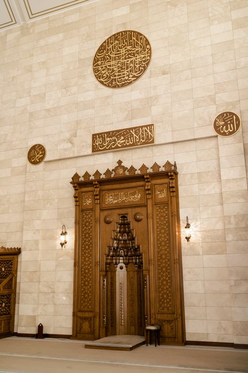 Free Intricate mosque interior featuring Arabic calligraphy and wooden craftsmanship. Stock Photo