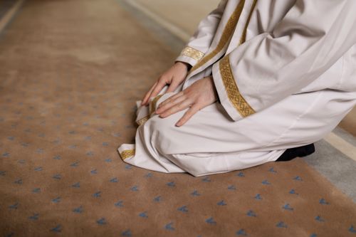 Free A man kneeling in prayer, wearing a traditional thawb during a religious moment. Stock Photo