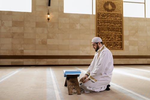 Man in Traditional Clothing Kneeling and Praying at Mosque