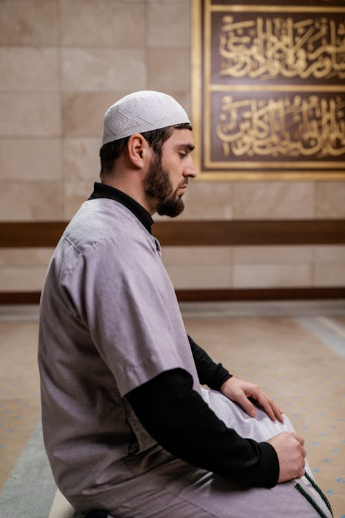 Man in Hat Praying at Mosque