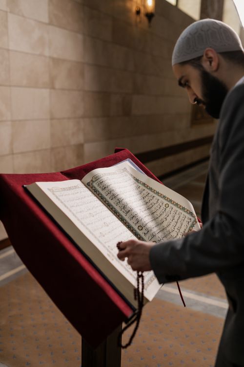 Free An adult man reading the Quran in a mosque, symbolizing spiritual devotion in Islamic culture. Stock Photo
