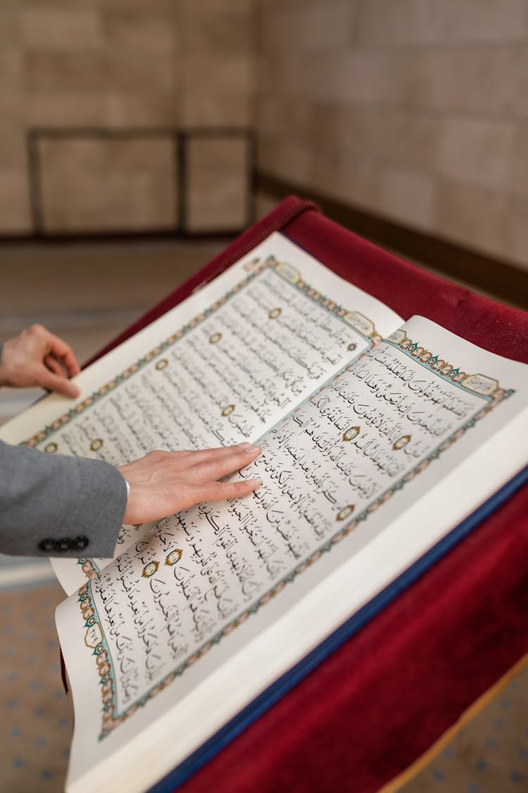 A Person Holding A Koran Book