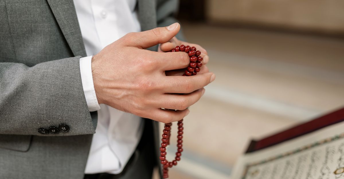 Rüyada Zikir Çekmek - Rüya Tabiri ve Anlamı - A person in formal attire holds prayer beads, reflecting Islamic culture and spirituality in a mosque setting.