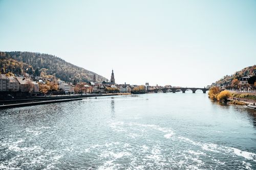 Free A picturesque view of Heidelberg's historic bridge and waterfront along the Neckar River. Stock Photo