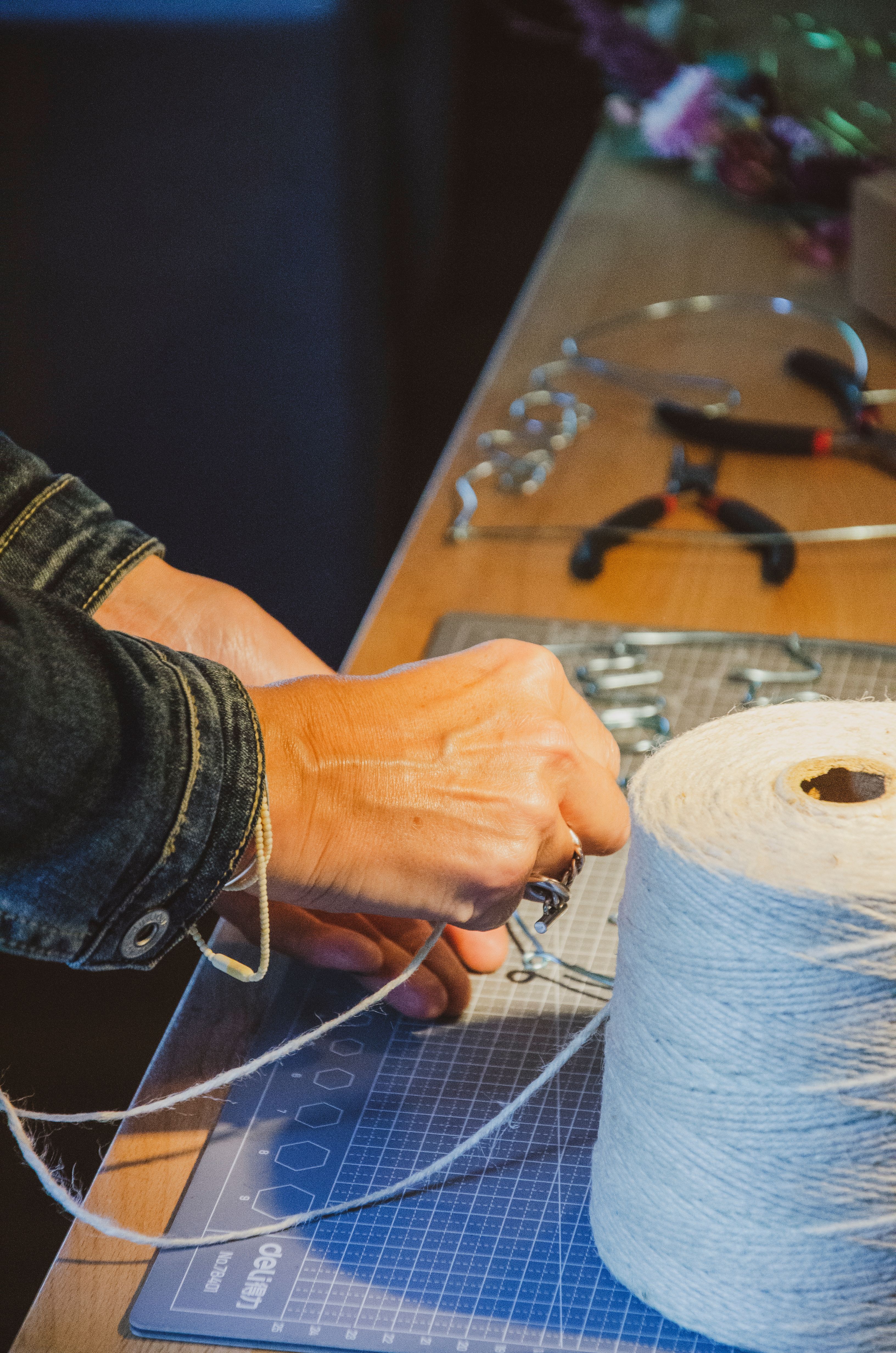 Mains travaillant une création textile avec pelotes et outils
