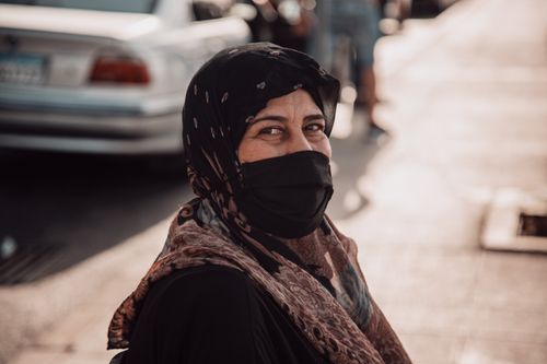 Free Portrait of a woman wearing a headscarf and face mask in urban setting. Stock Photo