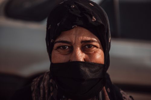 Free Close-up portrait of an elderly woman wearing a hijab and face mask, highlighting safety and cultural attire. Stock Photo