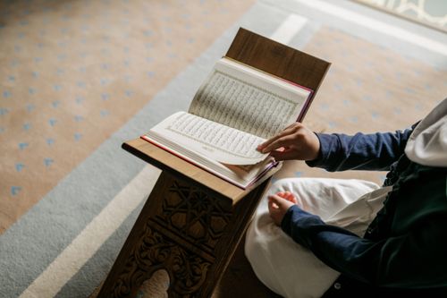 Free A young Muslim girl reading the Quran indoors, symbolizing devotion during Ramadan. Stock Photo