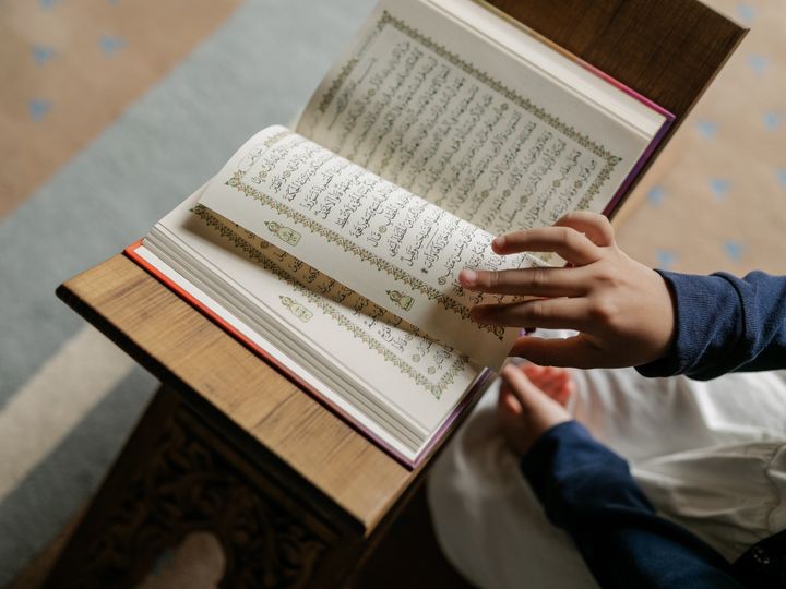 Little girl wearing hijab reading the Quran