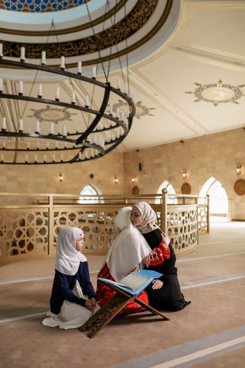 Free A Muslim mother and daughters bonding in a beautiful mosque interior, studying together. Stock Photo