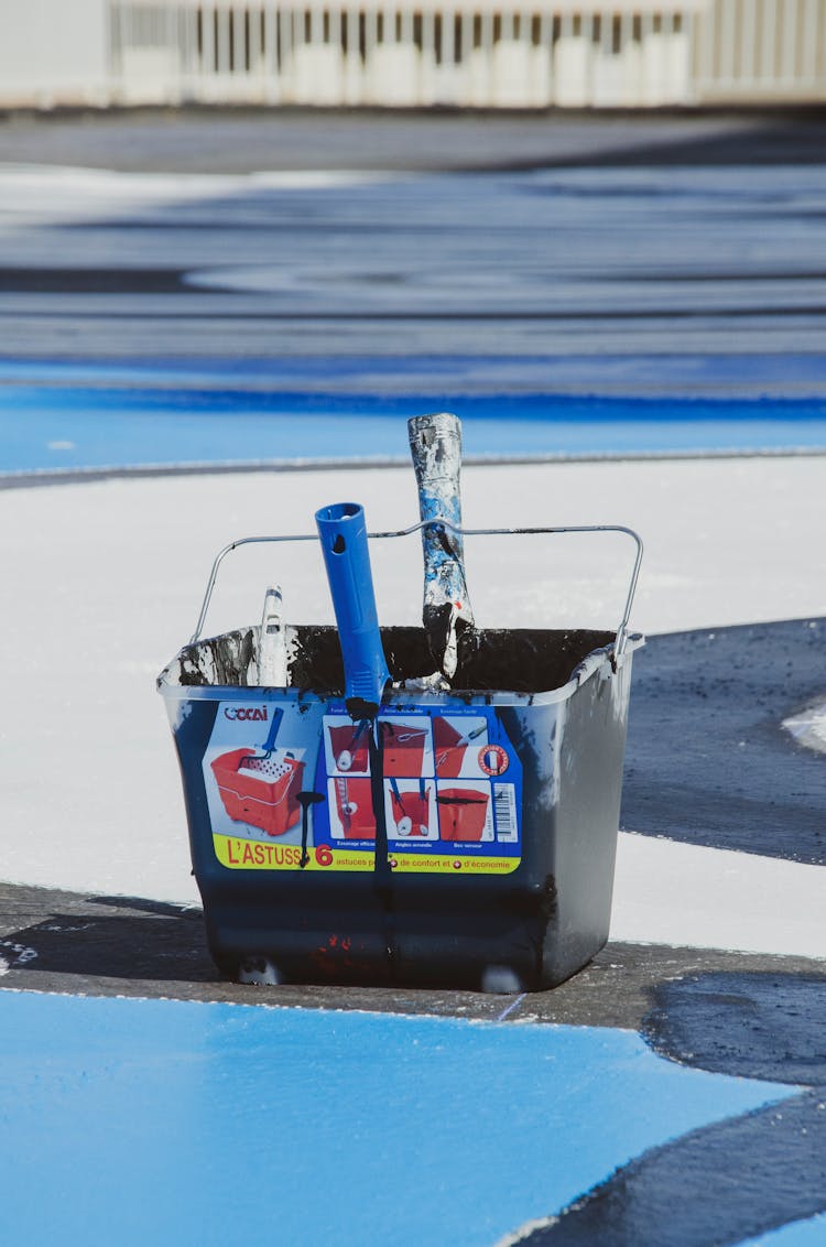 A Pail With Paint And Paintbrushes