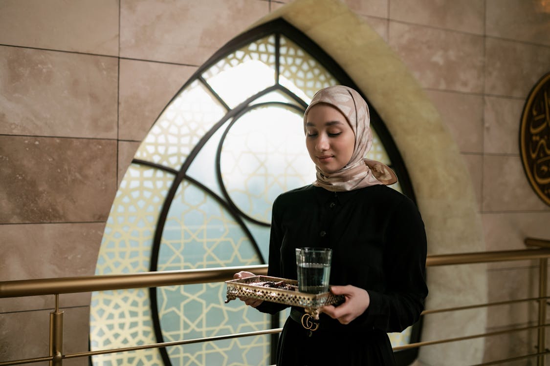 Free Woman with Headscarf Holding a Metallic Tray with Glass of Water Stock Photo