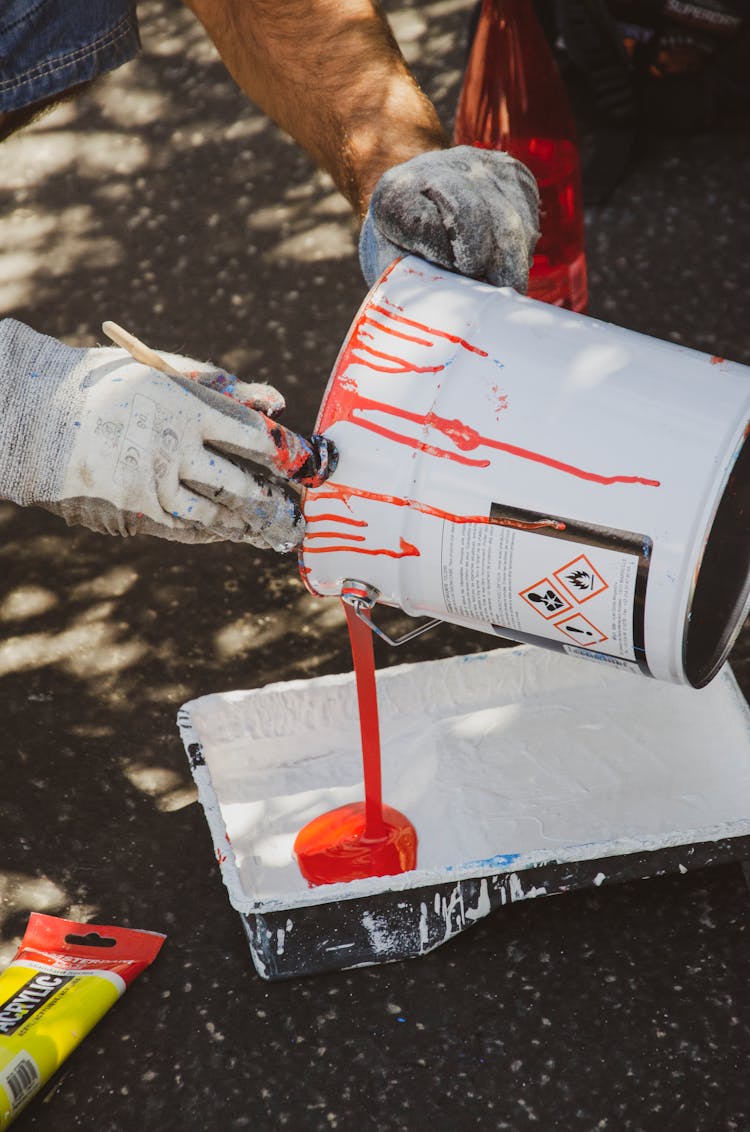 Person Pouring Red Paint On A Tray