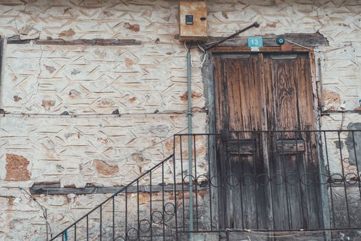 Detailed view of a rustic wooden door set in a vintage stone facade, featuring textured walls.