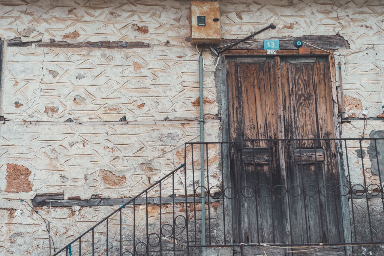 detailed view of a rustic wooden door set in a vintage stone facade fe