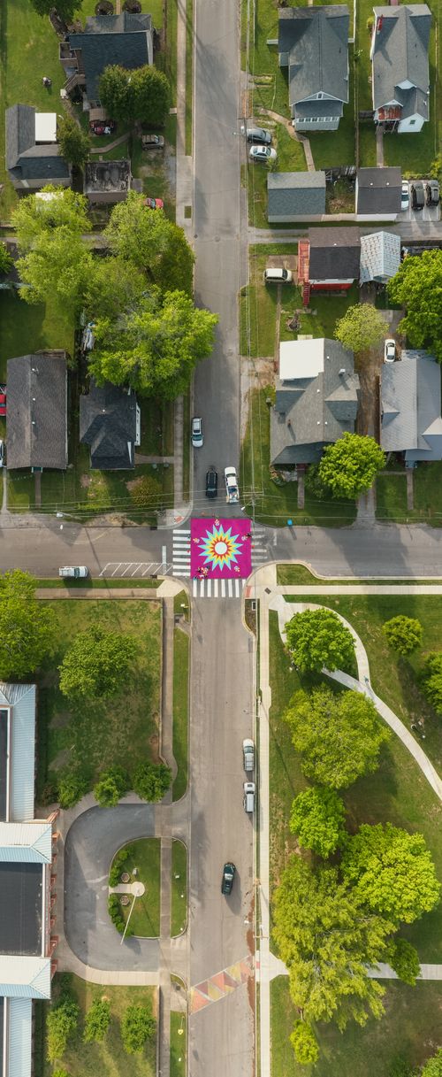 Free Vibrant urban neighborhood intersection with colorful street mural and surrounding houses. Stock Photo