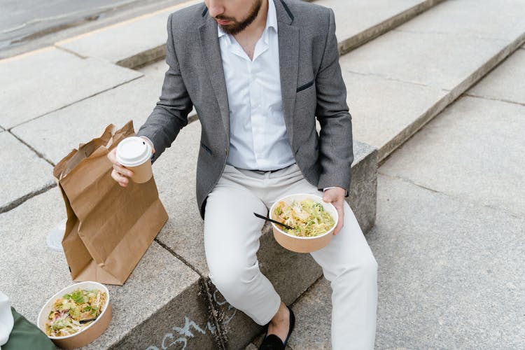 
A Bearded Man In A Suit Eating Takeaway Food