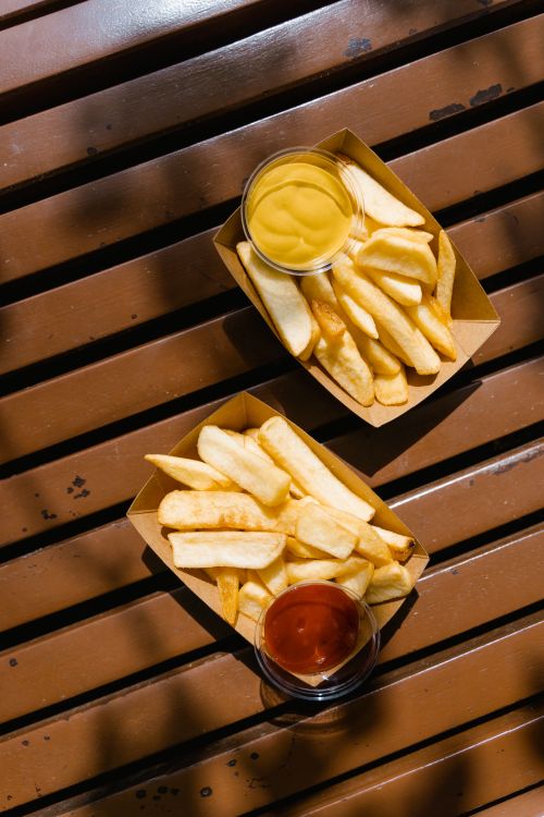 Free Golden French fries served with ketchup and mustard on a wooden bench. Perfect for fast food themes. Stock Photo