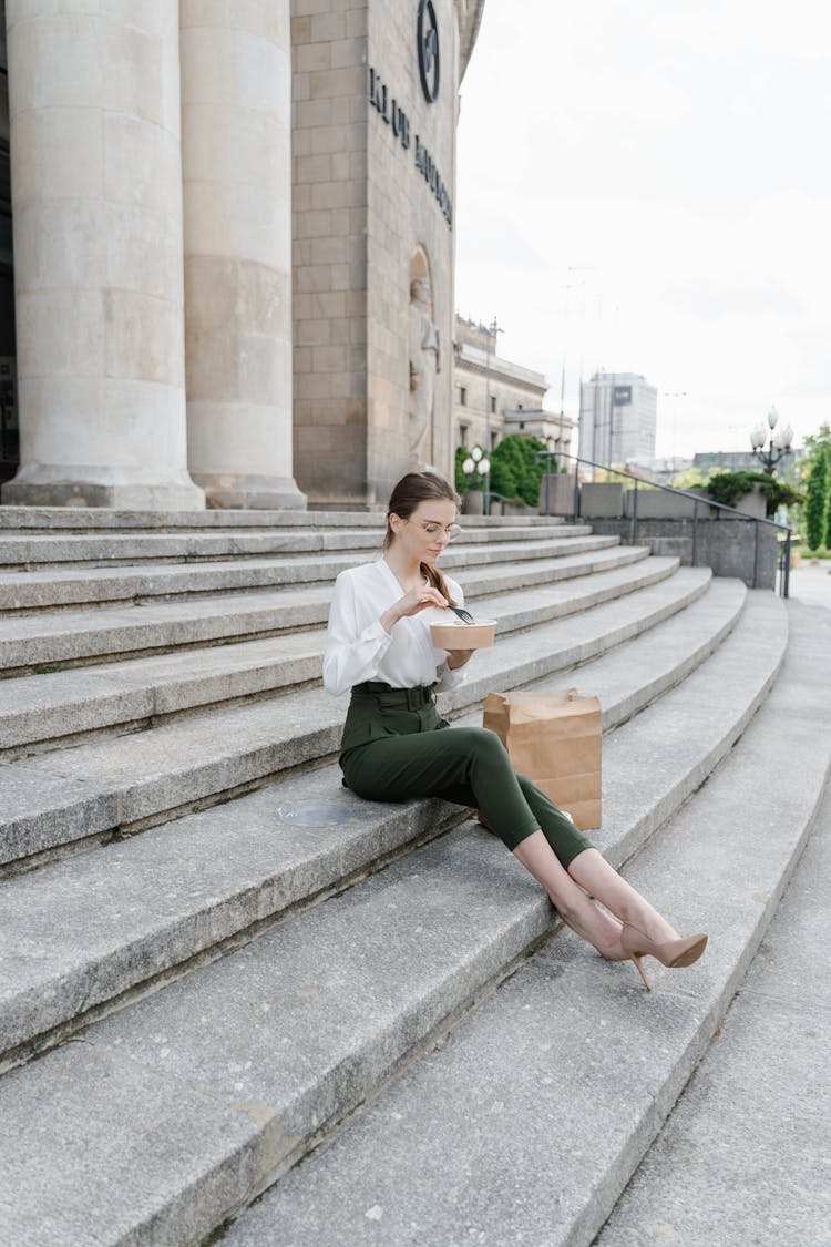 Female Professional Having Her Lunch On A Staircase 