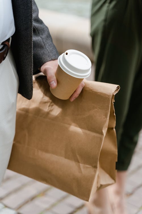 Free Person Holding a Food Takeaway Paper Bag and a Cup Stock Photo