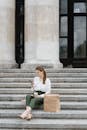 Woman in White Long Sleeve Shirt Sitting on Gray Concrete Stairs