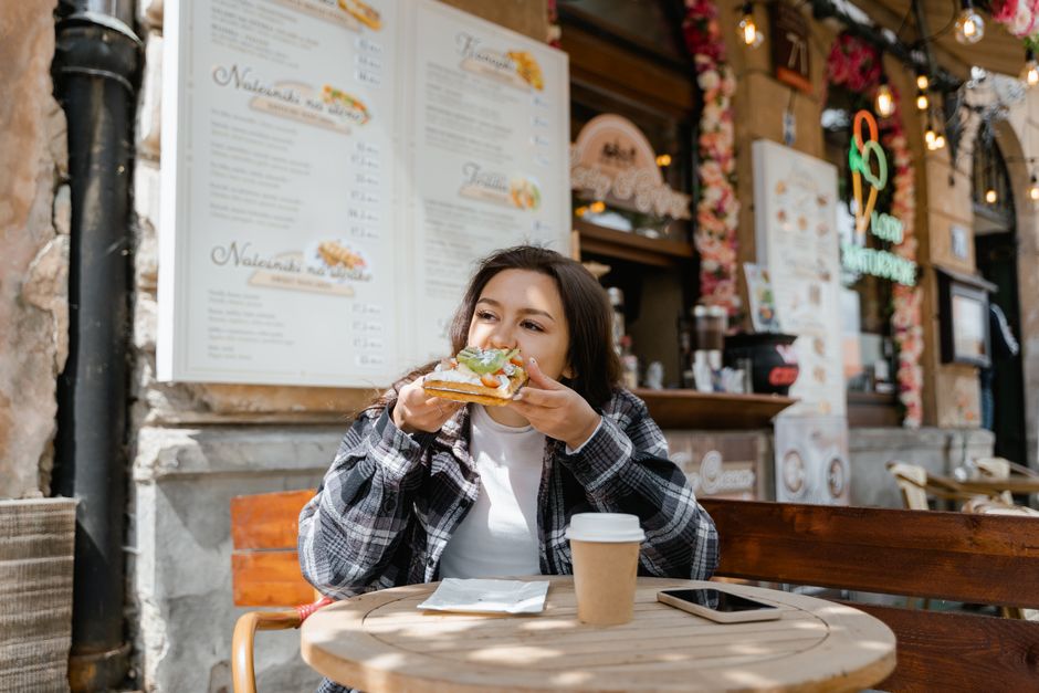 A group of college students laughing and eating casual meals at a cafe table