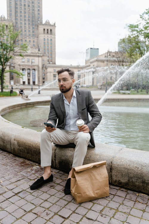 Man Sitting Beside a Water Fountain