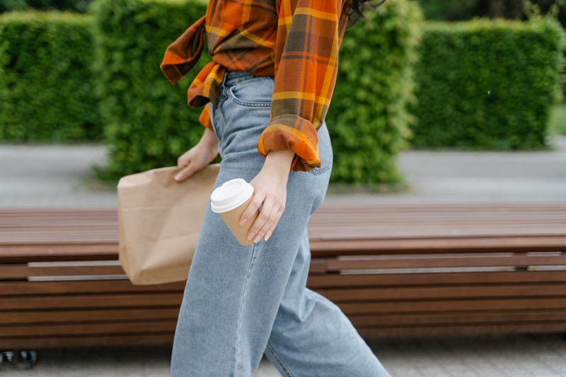 person walking toward a small coffee shop with cup in hand