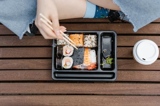 Overhead view of sushi and chopsticks during an outdoor picnic, perfect for a casual meal setting.