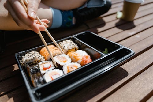 Close-up Photo of Person Picking Sushi using Chopsticks 