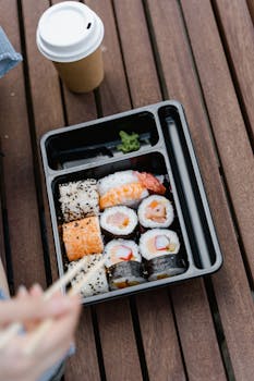 A savory sushi bento box with a coffee cup, perfect for an outdoor meal.