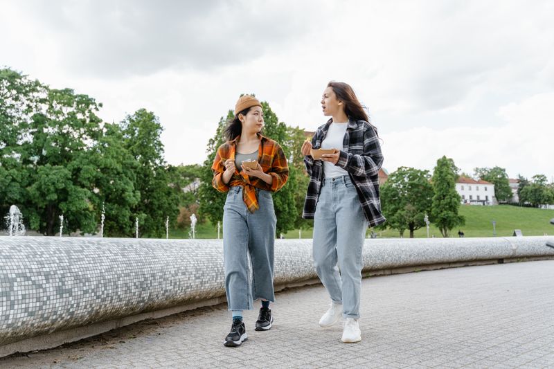 two coworkers walking outside while talking, holding phones