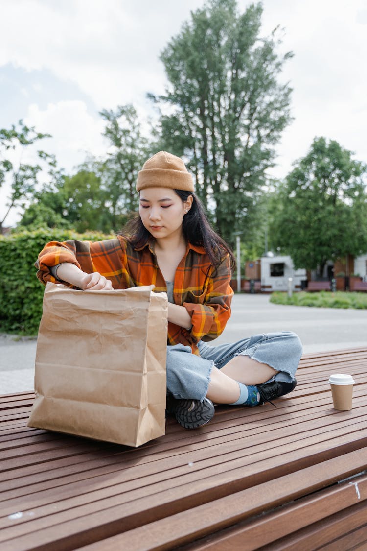 Woman In Plaid Shirt Opening Her Paper Bag