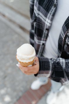 A person holds a delicious vanilla ice cream cone on a sunny day.